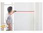 Homme utilise un télémètre laser pour marquer une ligne droite sur un mur.