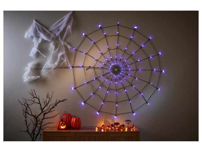 Halloween decoratie met verlicht spinnenweb, pompoenen en decoratieve paddenstoelen.