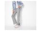 Femme en veste en jean bleu clair, haut blanc et pantalon côtelé gris avec baskets.