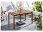 Table de jardin en bois avec parasol, chaise et plantes en extérieur.