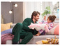 Een vader en dochter in pyjama's spelen met een knuffelpaard op de bank.