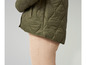 Veste matelassée verte et pantalon beige.