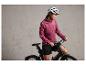 Een vrouw in een roze jack en fietshelm op een zwarte fiets