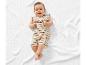 Lachende baby in gestreept setje op een wit kleed.