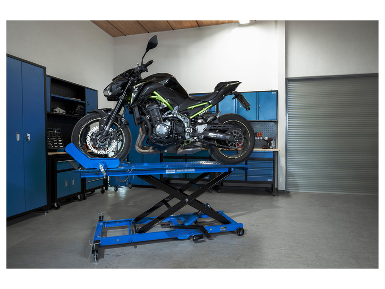 Une moto Kawasaki noire sur un pont élévateur hydraulique bleu pour moto.