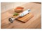 Mixeur plongeant blanc sur une planche à découper en bois à côté d'un bol de soupe de tomates.