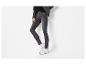 Femme portant un t-shirt noir, une veste en jean grise et un jean skinny gris avec des baskets blanches.