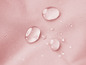 Waterdruppels op roze stof.