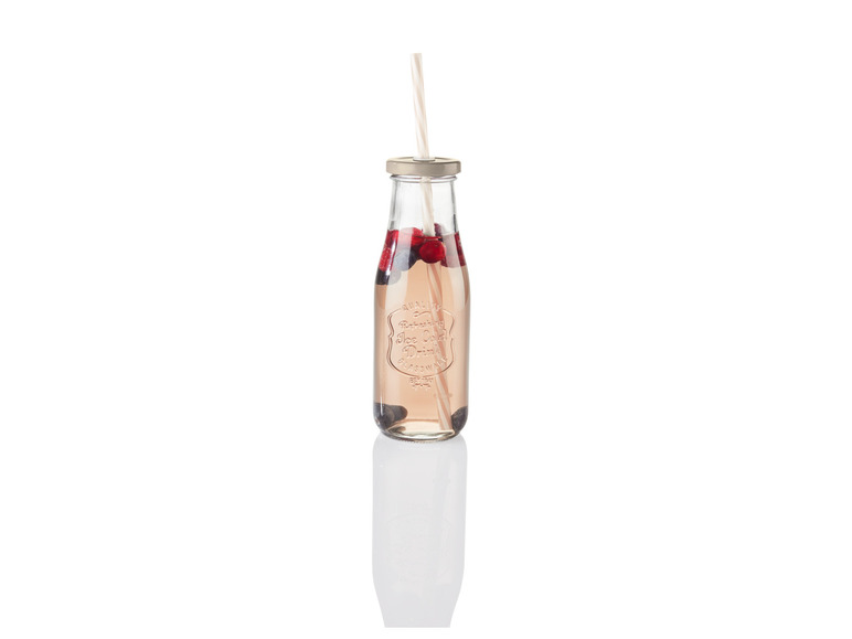 Une bouteille en verre avec une paille remplie de baies rouges et d'une boisson rose.