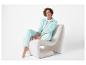 Vrouw in mintgroen trainingspak zit op een witte fauteuil.