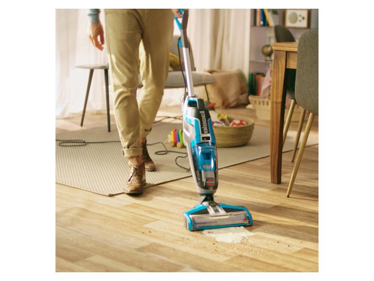 Een man gebruikt een Bissell Crosswave stofzuiger op een houten vloer.
