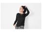 Femme en pull noir et jeans gris.