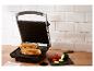 Paninigrill met twee gegrilde sandwiches en verse groenten op een houten tafel.