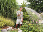 Un homme arrose des plantes dans le jardin avec un tuyau d'arrosage.
