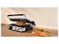 Grill met een sandwich, tomaten en basilicum op een houten tafel.