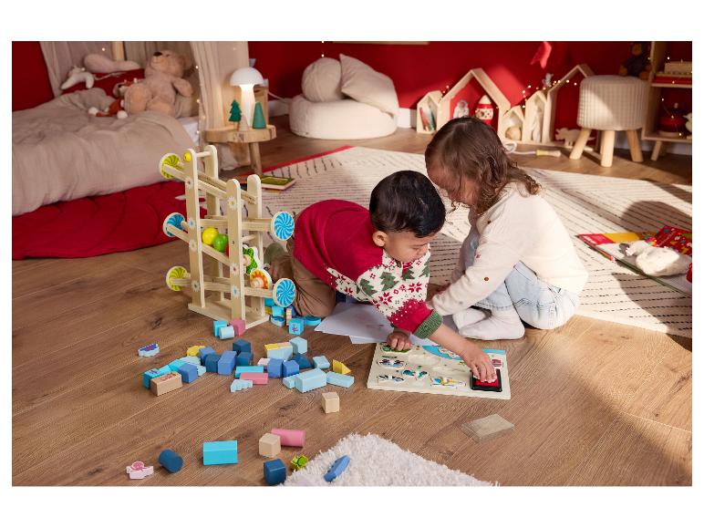 Deux enfants jouent sur le sol avec des jouets en bois et un puzzle.