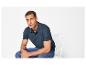Man in marineblauwe polo en jeans zit op een witte stoel