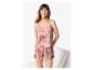Lachende vrouw in camisole en short pyjama met een roze en beige abstract patroon.