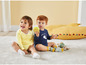 Twee baby's in gestreepte en blauwe rompers spelen op een vloerkleed.