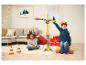 Deux enfants jouent avec une grue jouet et des cadeaux de Noël dans un salon.