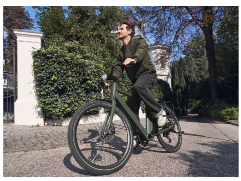 Man op een groene elektrische fiets in een woonstraat.