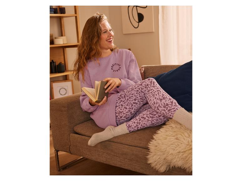 Femme sur un canapé avec un pull violet et un legging à imprimé léopard.