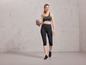 Een vrouw in sportkleding met een grijze fitnessbal van het merk Grit in haar handen.
