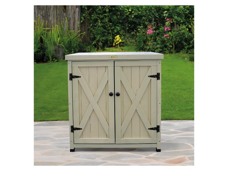 Armoire en bois à deux portes avec poignées noires sur une terrasse carrelée dans un jardin.