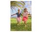 Twee meisjes in aardbeienprint tops en tule rokken rennend op gras.