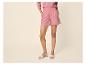 Femme en chemise et short roses, avec des sandales beiges.