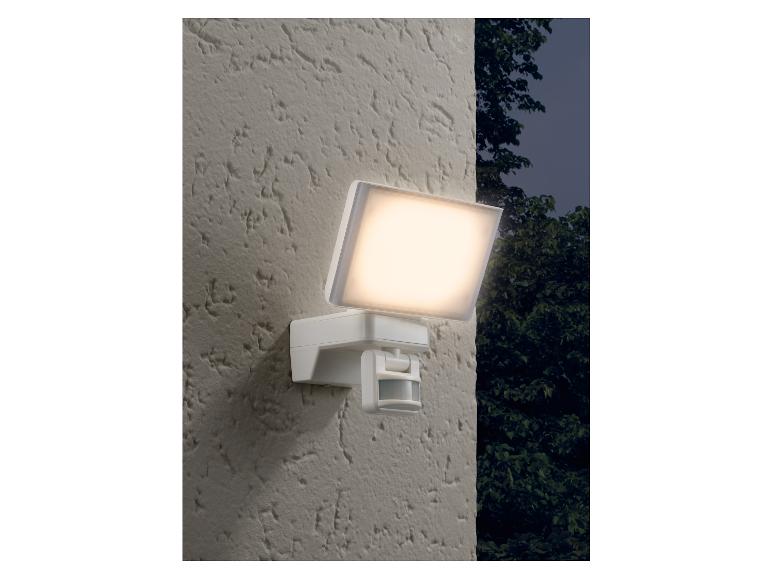 Un lampadaire extérieur blanc avec détecteur de mouvement, fixé à un mur.