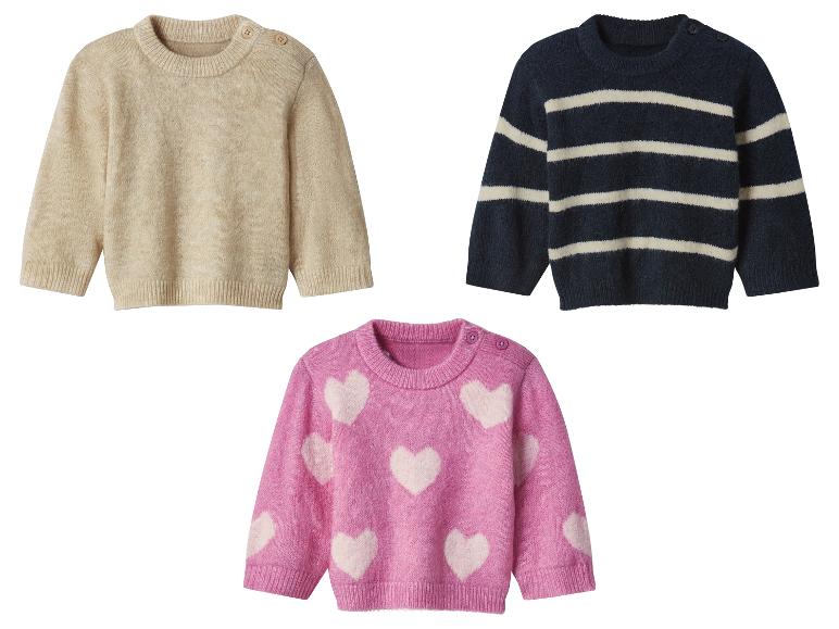 Drie kindertruien: een beige, een marineblauwe met witte strepen en een roze met witte harten.