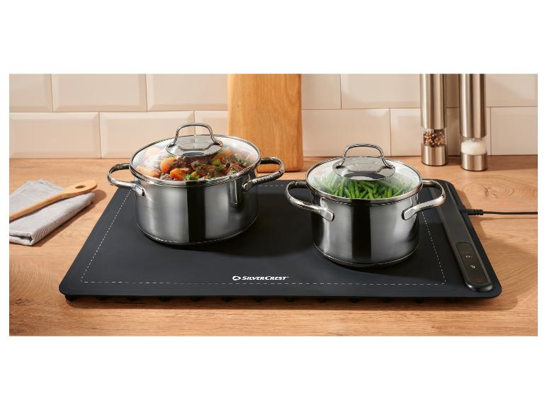 Casseroles avec de la nourriture sur un chauffe-plat électrique dans une cuisine en bois.