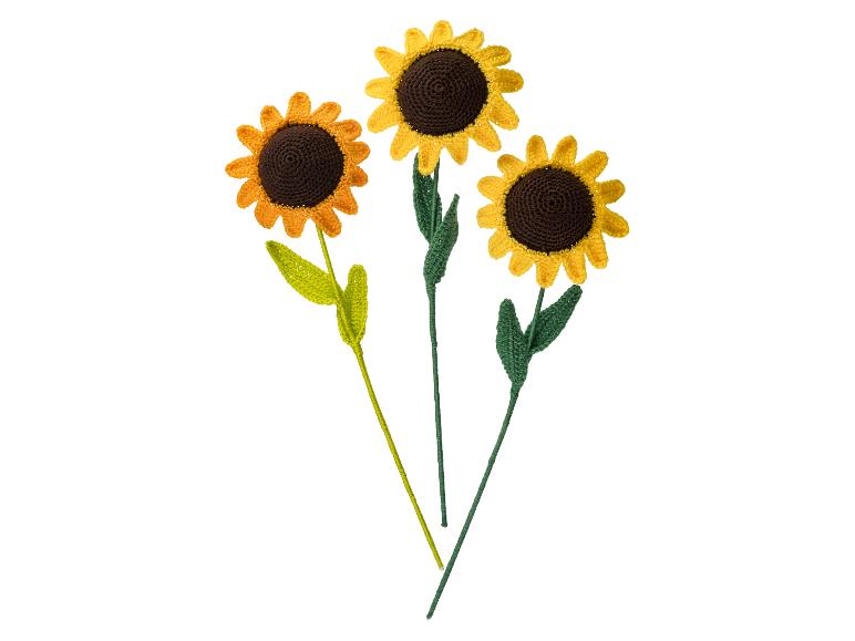 Trois tournesols au crochet avec des pétales jaunes et des centres bruns sur des tiges blanches