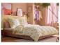 Chambre avec literie à motif de citrons, murs roses et portant à vêtements pastel.