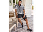 Man in een gestreepte polo, korte broek en loafers op een terras.