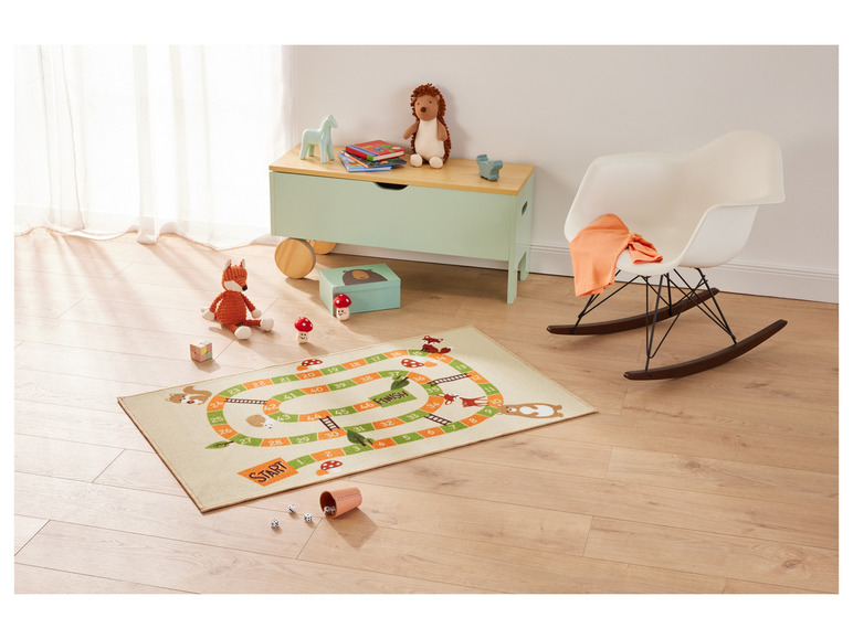 Een speelkleed met een bordspel voor kinderen, met dobbelstenen en een beker.