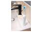 Brosse à dents électrique blanche avec tête de brosse bleue sur le bord d'un lavabo à côté d'un robinet noir.