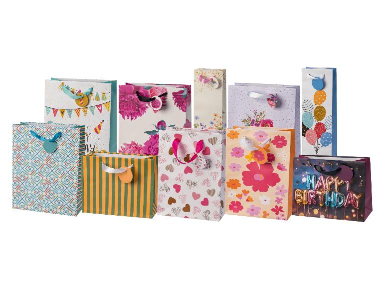 Assortiment de sacs cadeaux colorés avec divers motifs : fleurs, cœurs, rayures et texte 'Happy Birthday'.