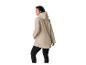 Vrouw in beige regenjas met capuchon en zwarte legging, met de rug naar de kijker
