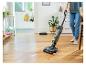Persoon reinigt houten vloer met een Bissell SpinWave Vac die gemorste vloeistoffen opruimt.