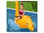 Une enfant s'amuse sur une bouée rhinocéros jaune dans une piscine.