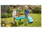Enfants jouant dans un jardin avec une table eau-sable, des jouets et des bulles de savon.