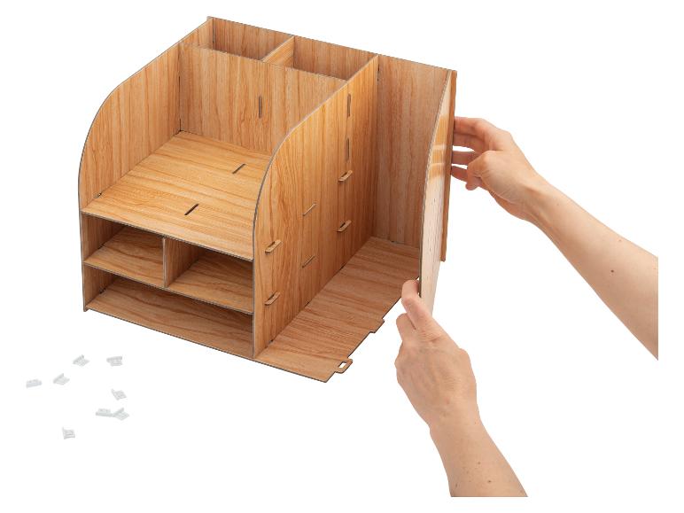 Handen monteren een houten bureau-organizer met meerdere vakken en planken.