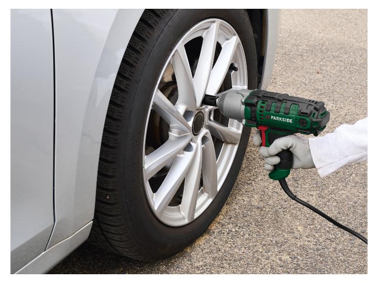 Personne utilisant une clé à chocs électrique pour changer un pneu de voiture.