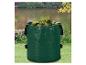 Sac vert pour déchets de jardin rempli de feuilles, devant un étang et un jardin.