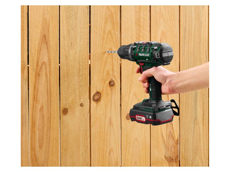 Une perceuse sans fil perce une clôture en bois.