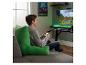 Jongere speelt videogame op groot scherm, zittend op bank met groot groen kussen.
