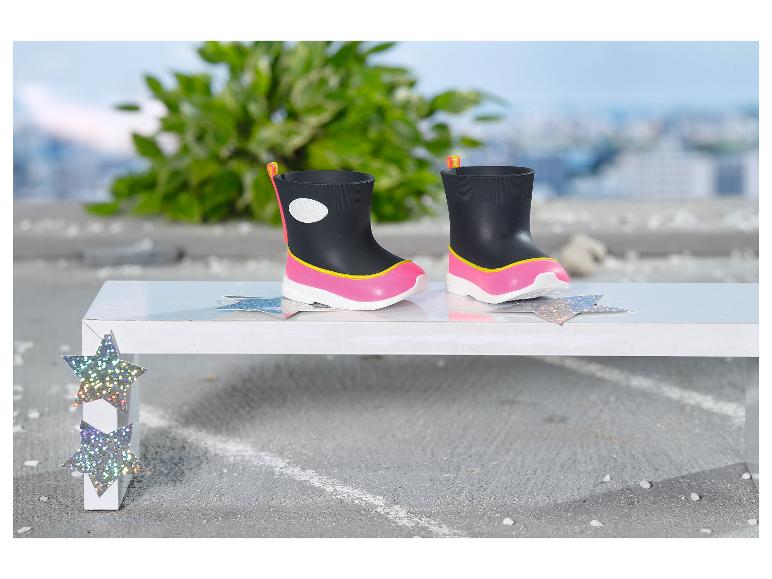 Bottes de pluie noires et roses pour enfants sur un banc blanc avec des décorations en étoile.