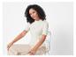 Een vrouw draagt ​​een witte top met korte mouwen en een beige broek.
